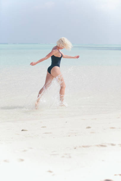 istock Woman in bikini running through water on sandy beach, Maldives 811849708