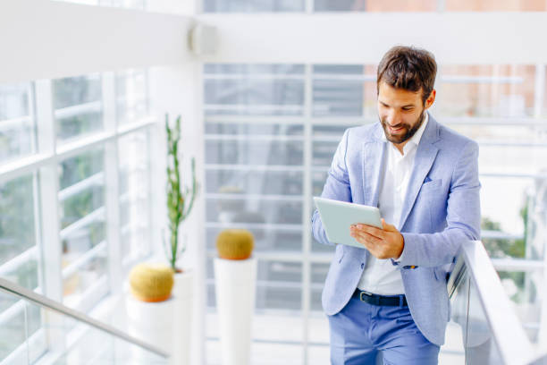 istock Handsome businessman with tablet on stairs 811870110