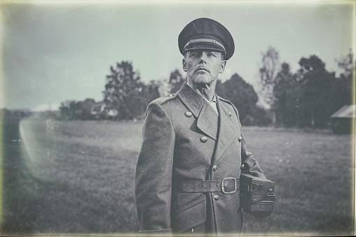 Antique black and white photo of 1940s military officer standing in field with phone.