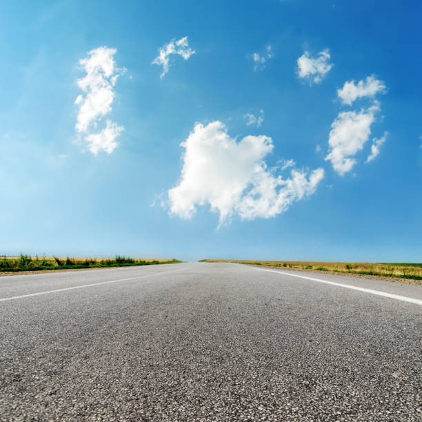 istock asphalt road closeup and clouds in blue sky 811880488
