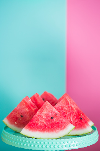 Watermelon slices on tray against pastel colored background.