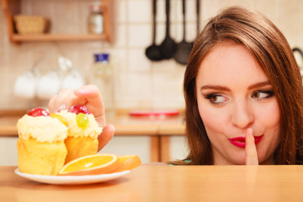 istock Woman eating cake showing quiet sign. Gluttony. 811897452