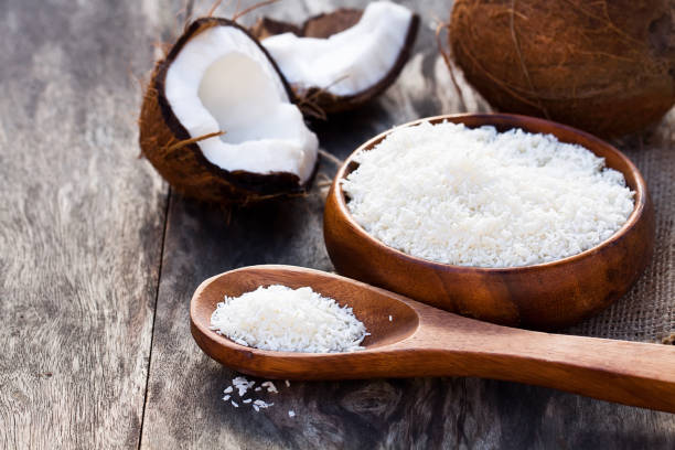 cocco incrinato e fiocchi su sfondo rustico del tavolo in legno - powdered coconut foto e immagini stock