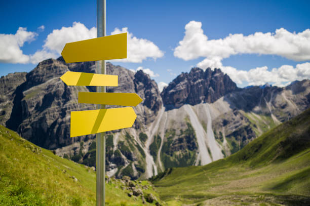 Blank hiking signs in the mountains Blank hiking signs on a pole in front of a blurred landscape with mountains and blue sky. hiking sign stock pictures, royalty-free photos & images