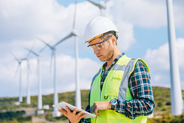 homme jeune ingénieur à la recherche et la vérification des éoliennes au champ - working windmill photos et images de collection