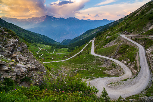 Camino de montaña de tierra conduce a paso de alta montaña en Italia (Colle delle Finestre). Expasive vista en el cielo espectacular puesta de sol, colorido, aventuras en el tiempo de verano, Alpes italianos. photo