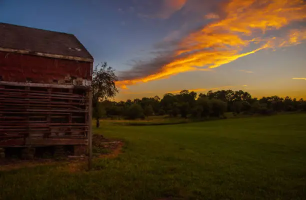 Sunset sky, meadow and old barn