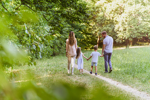 Family with two children walking away in the nature on a sunny day