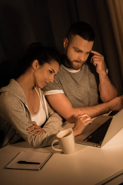 istock young pensive couple looking at laptop while sprnding time at home 811967724
