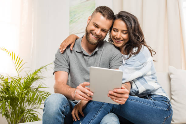istock young happy couple hugging and using digital tablet at home 811970288