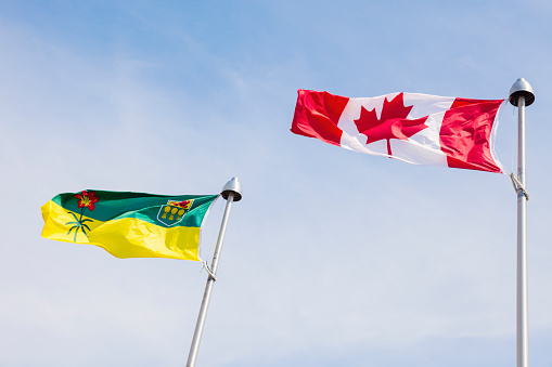 Saskatchewan and Canada flags against blue sky. Regina, Saskatchewan, Canada.