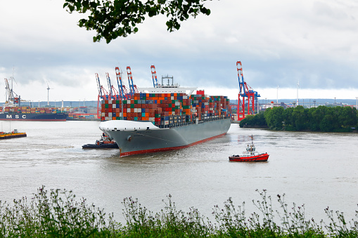 Stade, Germany – April 11, 2022: Container ship MONACO MAERSK on Elbe river heading to Hamburg, passing by survey ship WEDEL