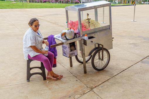 Brasilia, Brazil - February 28, 2017: Working in Brazil businesses theme. Female stallholder selling popcorn from mobile cart.