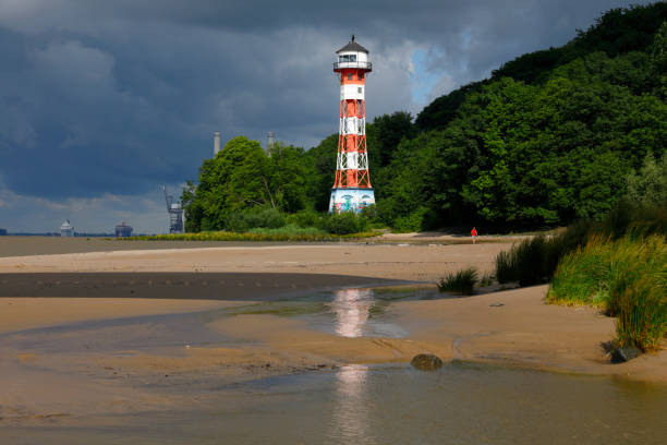 Falkenstein Lighthouse, Hamburg, Germany Hamburg, Germany - June 26, 2017: River Elbe Lighthouse (Falkensteiner Leuchturm) between Blankenese and Wedel, Hamburg, Germany. Man with red t-shirt jogging at the beach. övelgönne stock pictures, royalty-free photos & images