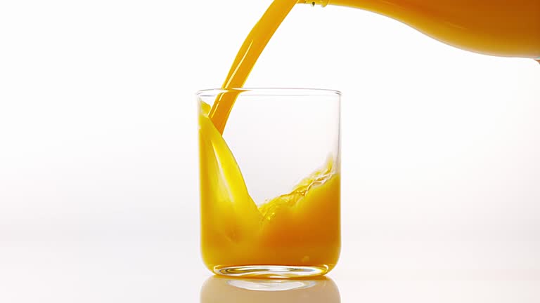 Orange Juice being poured into Glass against White Background, Slow Motion 4K