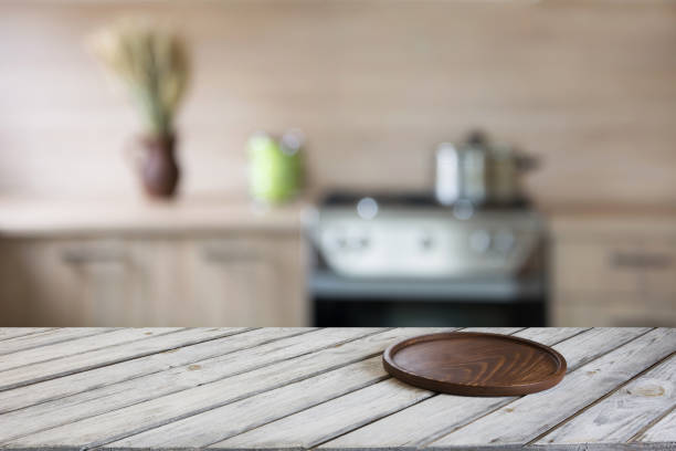 istock Blurred and abstract kitchen background. Empty wooden tabletop with cutting board  and defocused modern kitchen for display or montage your products. 812050068