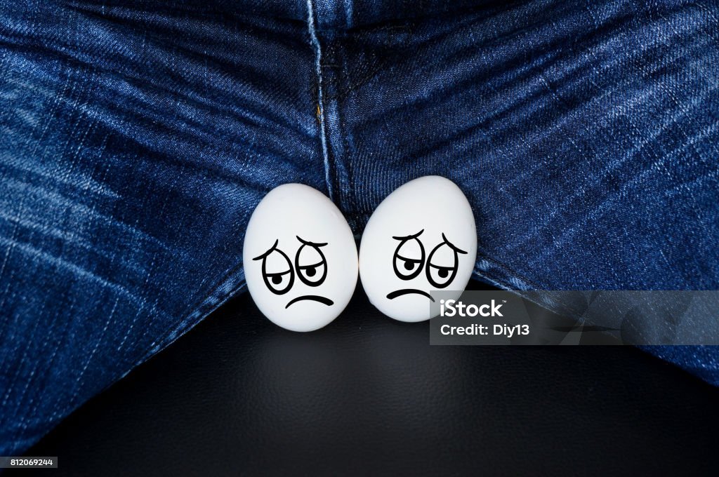 White eggs - a symbol of man's balls sad faces on the testicles of the guy. White eggs - a symbol of man's balls with the comic cartoon faces Testis Stock Photo