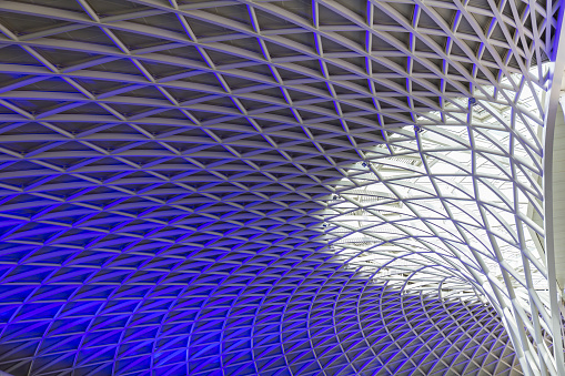 Sun shines through the triangulated roof at Kings Cross Station in London