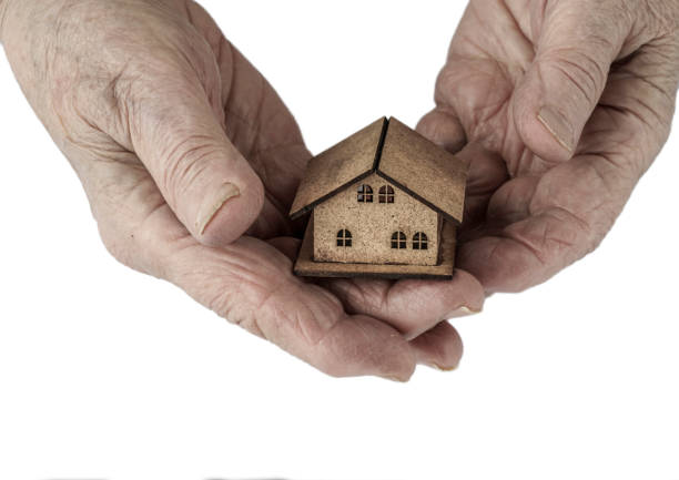 istock isolated wrinkled hands holding a small house on palm 812090794