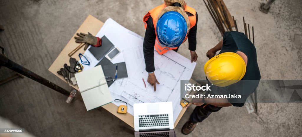 Checking the blueprints Two architects examining the blueprints on construction site Construction Site Stock Photo