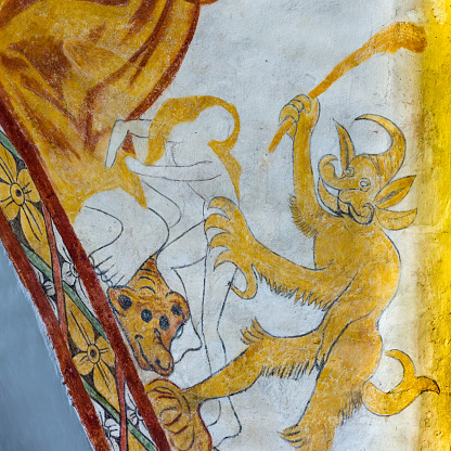 Devil takes woman in his clows, medieval gothic fresco in Vinderslev church, Denmark, June 22, 2017
