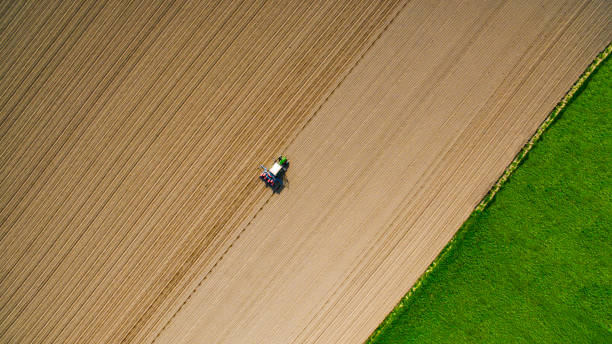 green tractor sowing in pavia prvince an aerial view of a green tractor sowing on field in pavia province, during a sunny day lombardy photos stock pictures, royalty-free photos & images