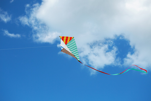 Flying kite in the blue sky against the background of clouds