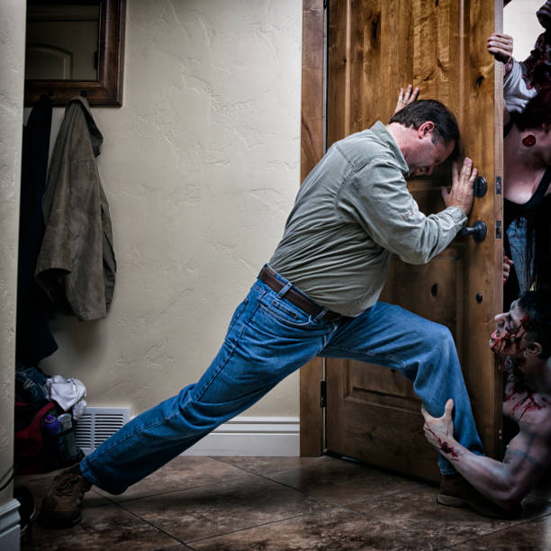 Man straining to hold the door closed as zombies are trying to break in.