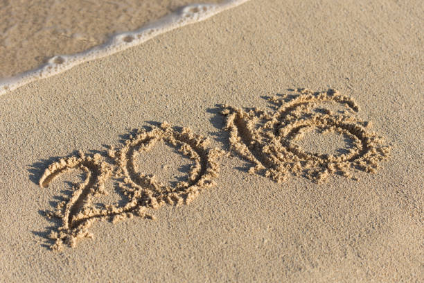 istock Inscription 2016 on sandy beach with wave's foam 812184190