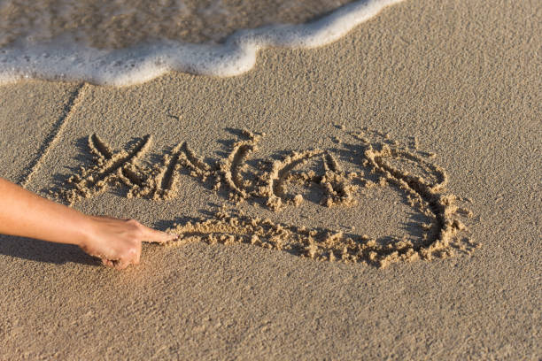 istock Female hand writting Xmas on sandy beach with wave's foam 812192946