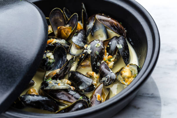 Soup of mussels creamy Soup of mussels creamy in black bowl on marbel surface. mussel stock pictures, royalty-free photos & images