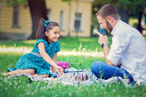 kleines mädchen spielt schach mit ihrem vater und versuchen zu betrügen - smart casual occupation casual healthy eating stock-fotos und bilder