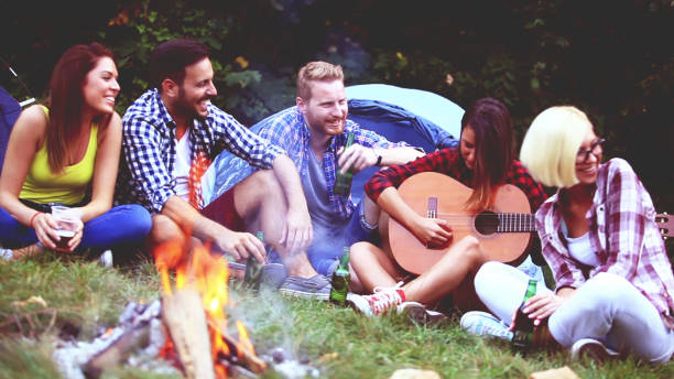 istock Five friends sitting next to campfire and singing song 812214162