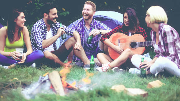 istock Five friends sitting next to campfire and singing song 812214480
