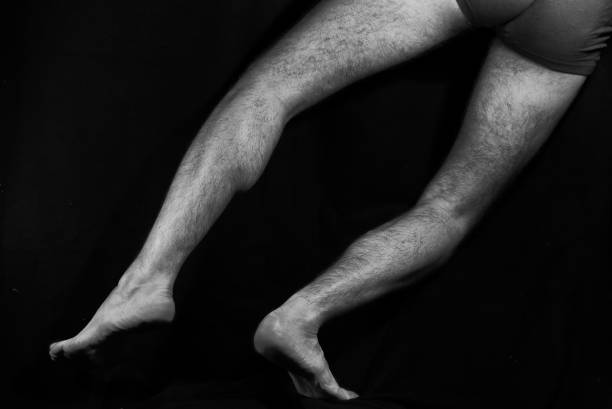 beautiful, muscular, bare male feet on a black background - motion art naked studio shot imagens e fotografias de stock