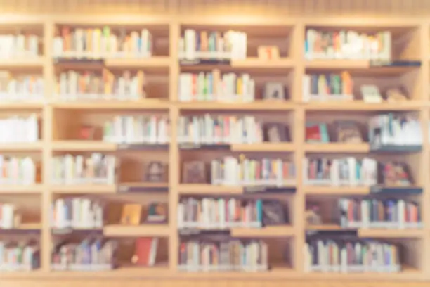 blurred bookshelf in library room for your background design - vintage color styles.