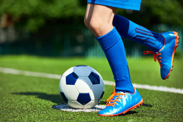 gambe giocatore di calcio ragazzo con stivali con palla sull'erba - soccer socks foto e immagini stock