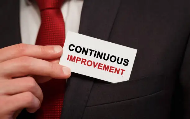 Photo of Businessman putting a card with text Continuous improvement in the pocket