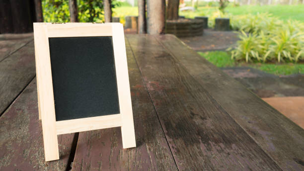 istock Blank wooden blackboard frame on wood floor. Empty chalkboard. 812383950