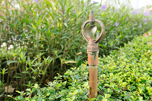 Old rusty vintage sprinkler water in green garden.