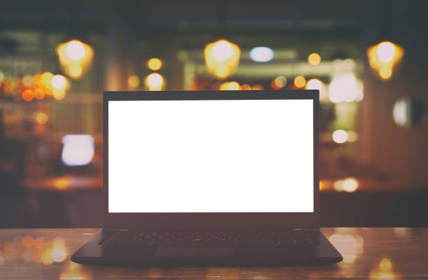 istock open laptop with white screen on wooden table in front of abstract blurred restaurant lights background. 812408462