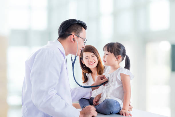 Asian doctor examining a girl by stethoscope stock photo