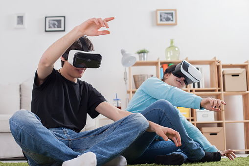 Virtual reality. Teens with virtual glasses are playing in the living room