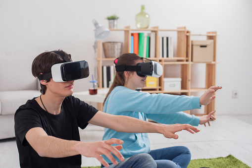 Virtual reality. Teens with virtual glasses are playing in the living room