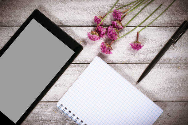 istock workspace with notebook and tablet.flowers on wooden background with copy space.  celebration template concept. 812460992