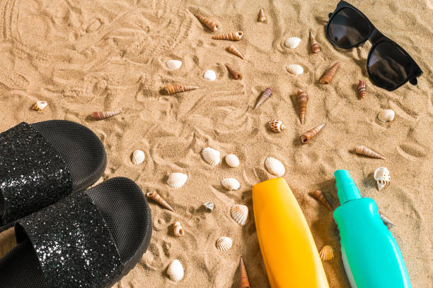 istock Black flip-flops and sunglass, seashell on sand. With place for your text. Top view 812469392