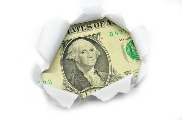 istock US currency macro peeking through torn white paper. 812470554