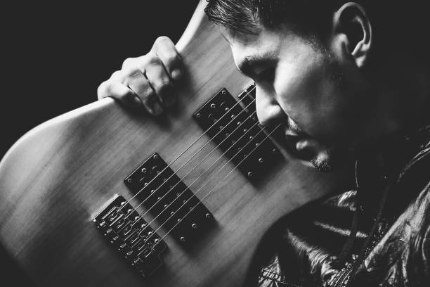 istock asian handsome rocker in black jacket posing on electric guitar, black and white 812473708