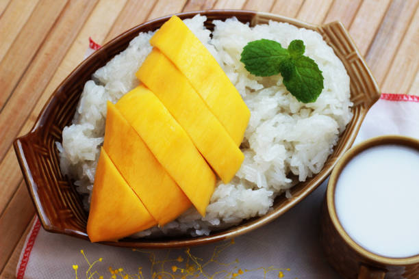 istock Mango sticky rice is put in a wooden container placed on a brown wooden table 812484784