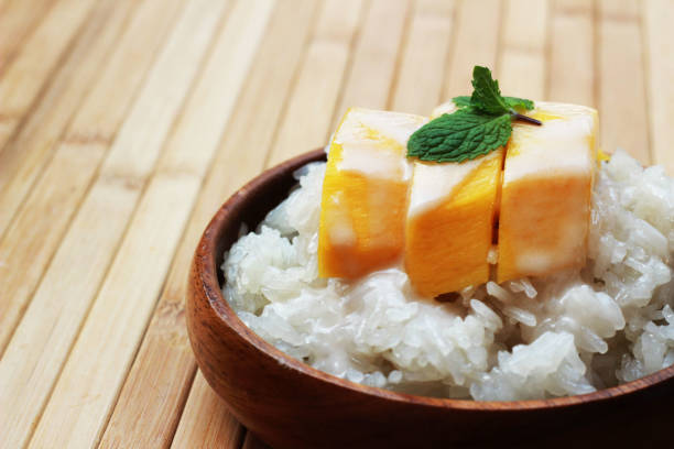 istock Mango sticky rice is put in a wooden container placed on a brown wooden table 812484844